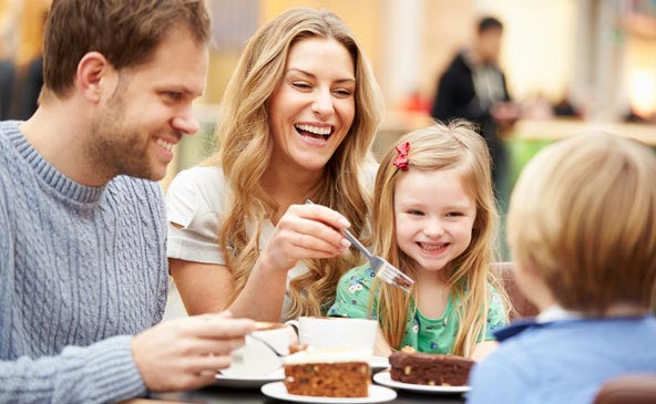 Glückliche und lachende Familie, zusammen beim Kaffee und Kuchen im Four You